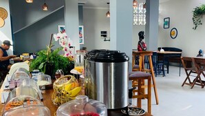 A breakfast buffet with various fruits, a coffee station, and seating areas. - Pousada Vila de Charme (Barreirinhas)