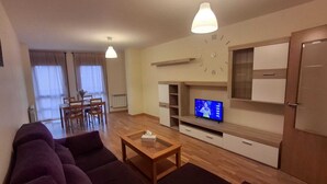 Ein modernes Wohnzimmer mit einer Sofagarnitur, einem Couchtisch, einem Fernseher und Einbauschränken.