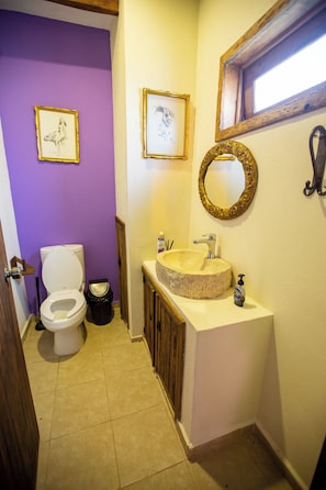 Une salle de bain avec des toilettes, un lavabo et des tableaux encadrés accrochés au mur.