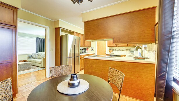 Una cocina moderna con armarios de madera, un refrigerador de acero inoxidable y un comedor con una mesa redonda y sillas.