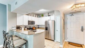 A modern kitchen with white cabinets, stainless steel appliances, and a granite countertop. - 1 Mi to Henderson Beach: Condo w/ Resort Perks! (Destin)