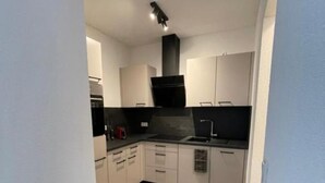 Una cocina moderna con armarios blancos, encimera negra y una isla central.