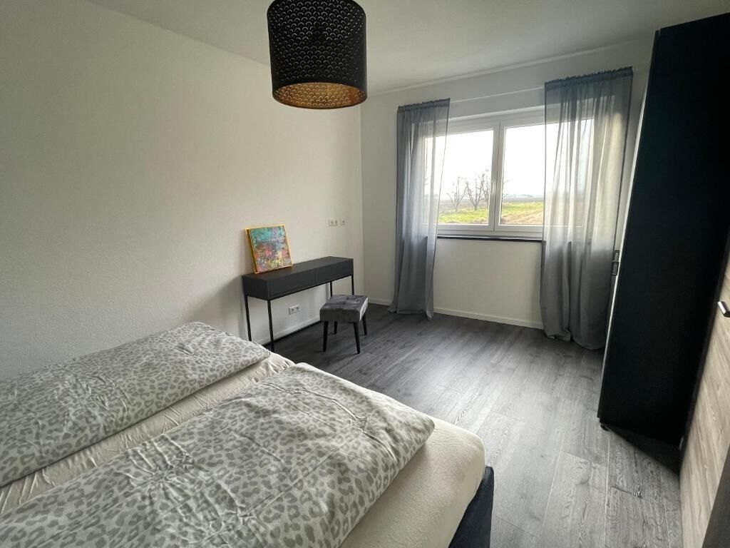 Une chambre à coucher avec un lit, un bureau, une chaise et une fenêtre avec des rideaux.