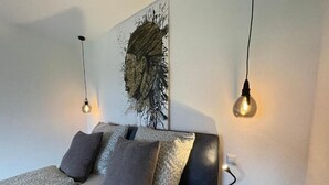 Un dormitorio moderno con cama, cabecera y lámpara de pared.
