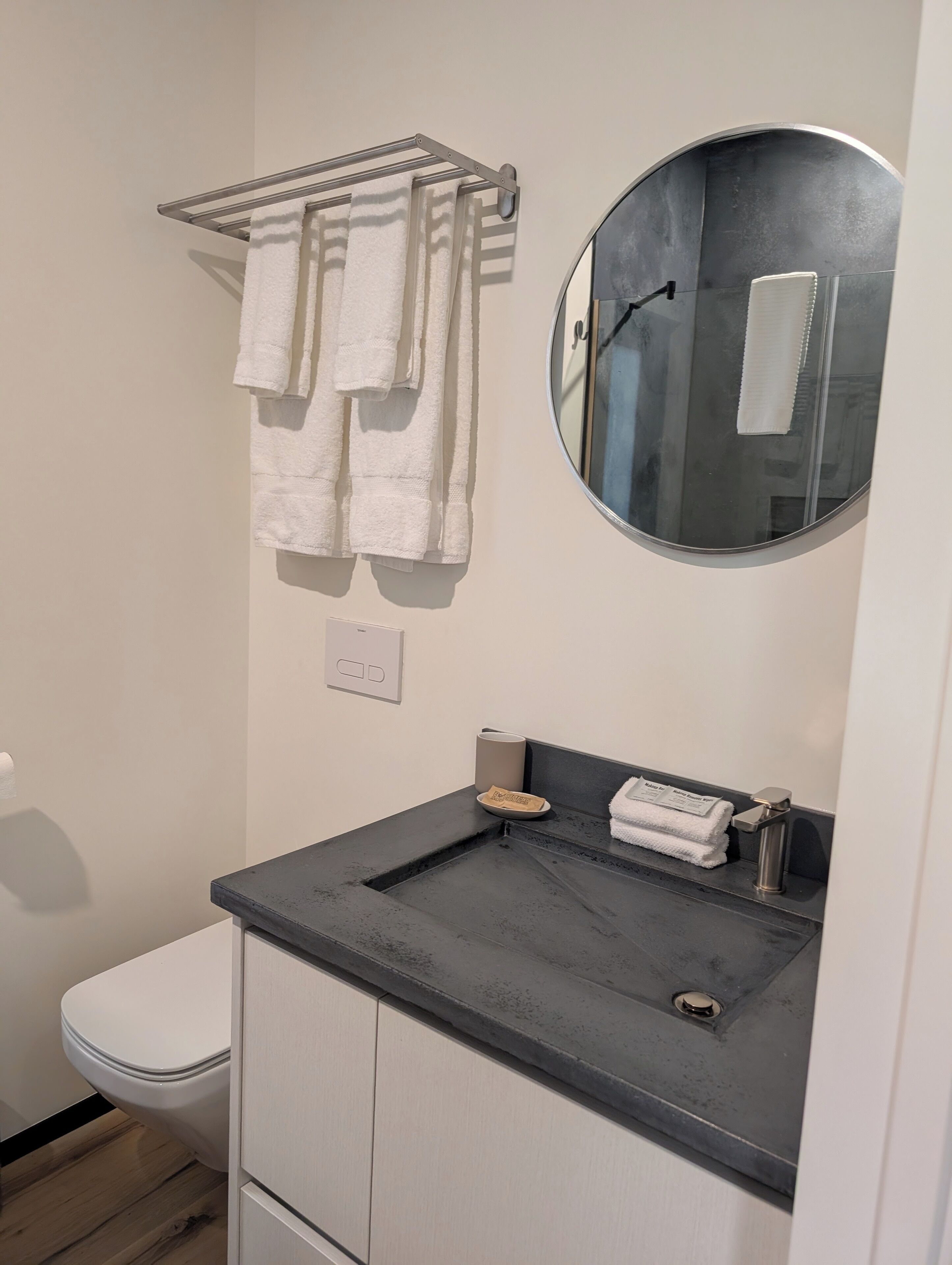 A bathroom with a toilet, a sink with a mirror, and a towel rack with towels.