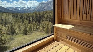 Ein Holzsaunaraum mit einem großen Fenster und Blick auf die Berge.