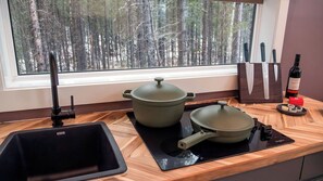 A kitchen with a large window, a sink, a stove, and a knife block.