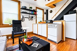 Une cuisine compacte équipée d’une cuisinière, d’un four à micro-ondes et d’un petit coin repas avec une chaise et une table.