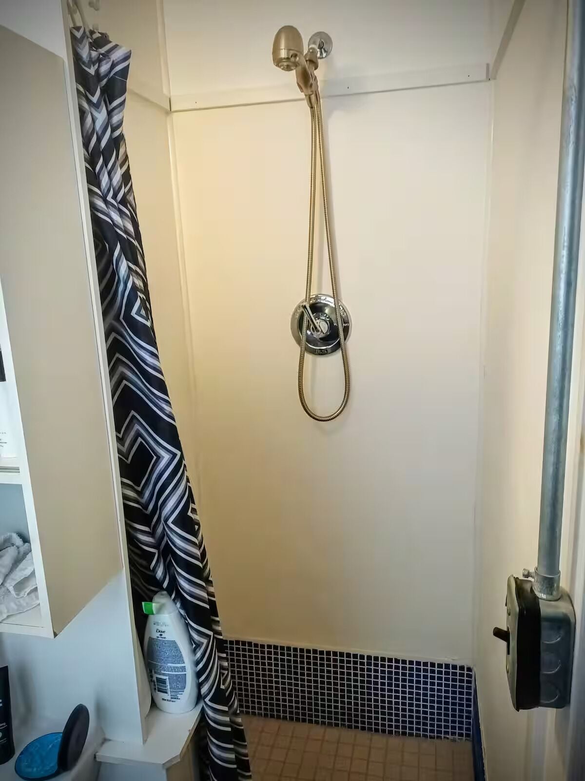 Ein kleines Badezimmer mit Dusche, Handtuchhalter und Toilette.