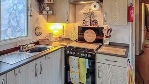 A compact kitchen with a sink, stove, and wooden cabinets. - 3 bedroom accommodation in Hawick (Hawick)