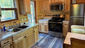 A compact kitchen with wooden cabinets, a stainless steel refrigerator, a microwave, and a stove. - Shady Rest Cabin #4, Sunset Views, Sandy Beach, Fishing, Trails, Firepit (Rhinelanderi)