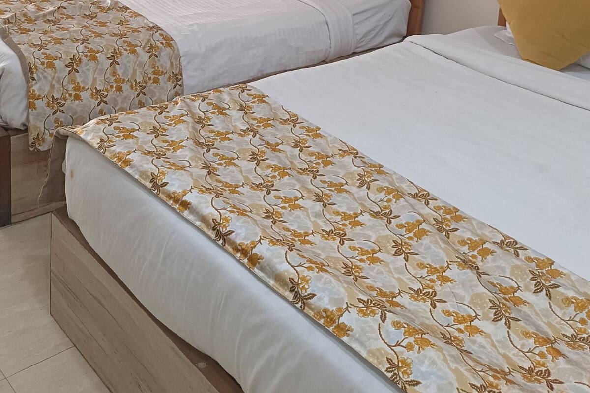 A hotel room with two beds, a painting on the wall, and a mirror.