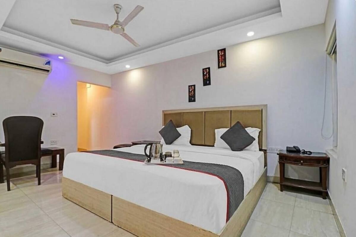 A hotel room with a bed, a chair, a bedside table, and a ceiling fan.