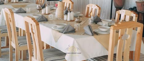 A dining table set with white tablecloth, wooden chairs, and various tableware.