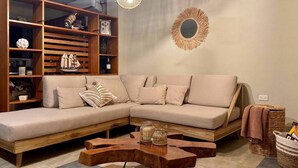 Een moderne woonkamer met een hoekbank, houten planken en decoratieve objecten.
