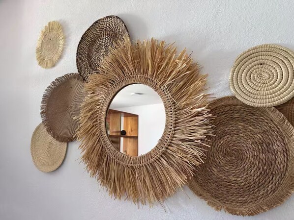 Una pared decorada con varios tapices tejidos y un espejo.