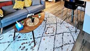 Un salon moderne avec un canapé gris, une table basse et un tapis à motifs.
