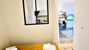 Une chambre d’hôtel avec un lit, un miroir, un plancher en bois et une vue sur la cuisine et la salle à manger.