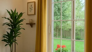 Een kamer met een grote schuifdeur, een potplant, een rieten mand en een ingelijste foto aan de muur.