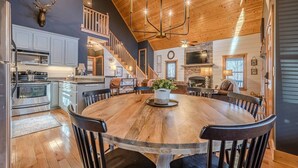 A spacious kitchen with modern appliances, a dining area with a large wooden table, and a cozy living room with a fireplace. - Cozy Dahlonega Cabin w/ Hot Tub. Surrounded by wineries and 8 mins to downtown! (Lumpkin County)