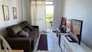 Ein Wohnzimmer mit einem braunen Sofa, einem Fernseher und einem gelben Sessel.