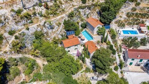 An aerial view of a residential area with stone buildings, a swimming pool, and surrounding greenery. - Villa Eden - two charming stone houses with sea views by MyWaycation (Omis)
