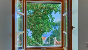 A window with a view of a tree and a building with a red roof. - Villa Eden - two charming stone houses with sea views by MyWaycation (Omis)
