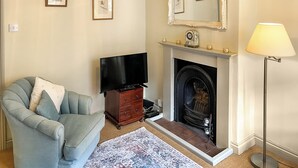 A living room with a sofa, a flat-screen TV, a fireplace, and a lamp.