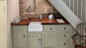 A kitchen with a stone wall, a sink, a scale, and a small decorative item on the counter.