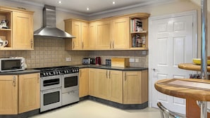 A modern kitchen with wooden cabinets, a built-in microwave, a stove, and a toaster.