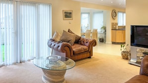 A spacious living room with a leather sofa, a glass coffee table, and a television.