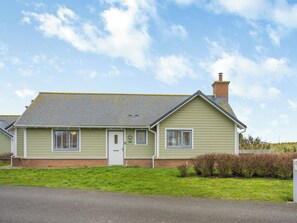 Une maison de plain-pied avec un toit à pignon, une porte d’entrée et deux fenêtres sur le côté.
