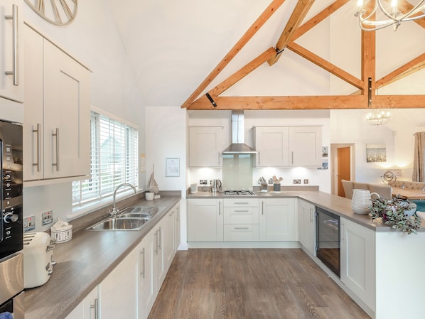 A modern kitchen with white cabinetry, a wooden ceiling, and a built-in dishwasher.