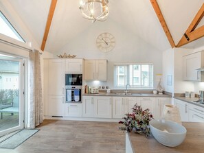 A kitchen with white cabinets, a built-in oven, a sink, and a window. - 2 bedroom accommodation in Beadnell (Beadnell)