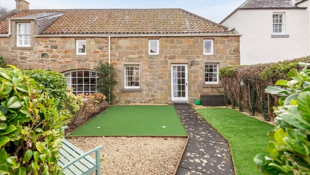 A stone house with a green lawn and a gravel area.
