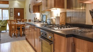 A kitchen with wooden cabinets, a gas stove, and a dining area with a table and chairs.