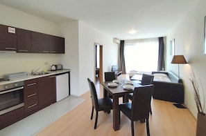 Una cocina moderna con armarios oscuros, un refrigerador blanco y un comedor con una mesa dispuesta para cuatro.