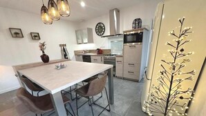 Une cuisine moderne avec un coin repas, comprenant une grande table, des chaises et un luminaire décoratif.