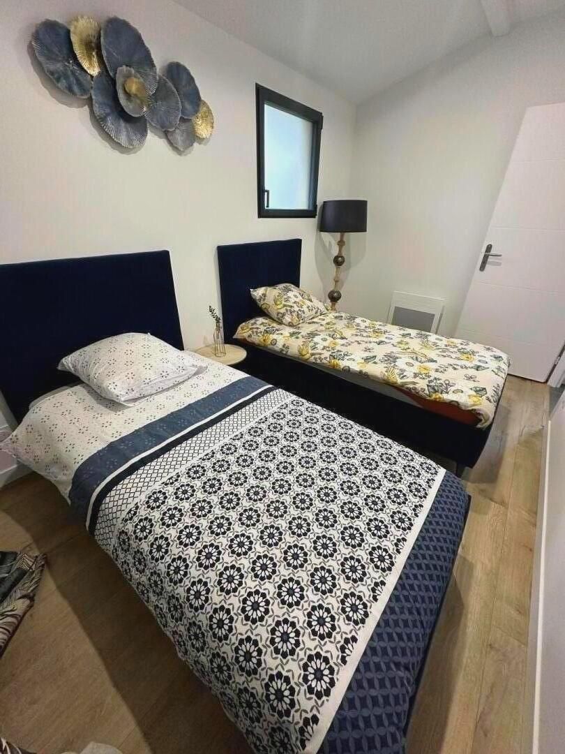 Un dormitorio con dos camas, una mesita de noche, una lámpara y un adorno en la pared.