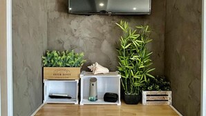 Ein zeitgemäßer Wohnraum mit flachbildfernseher an der Wand, einem Holztisch mit Staufächern und dekorativen Pflanzen.