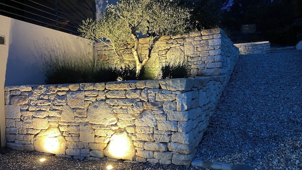 Eine steinerne Stützmauer mit einem Baum und einer kleinen Gartenanlage.