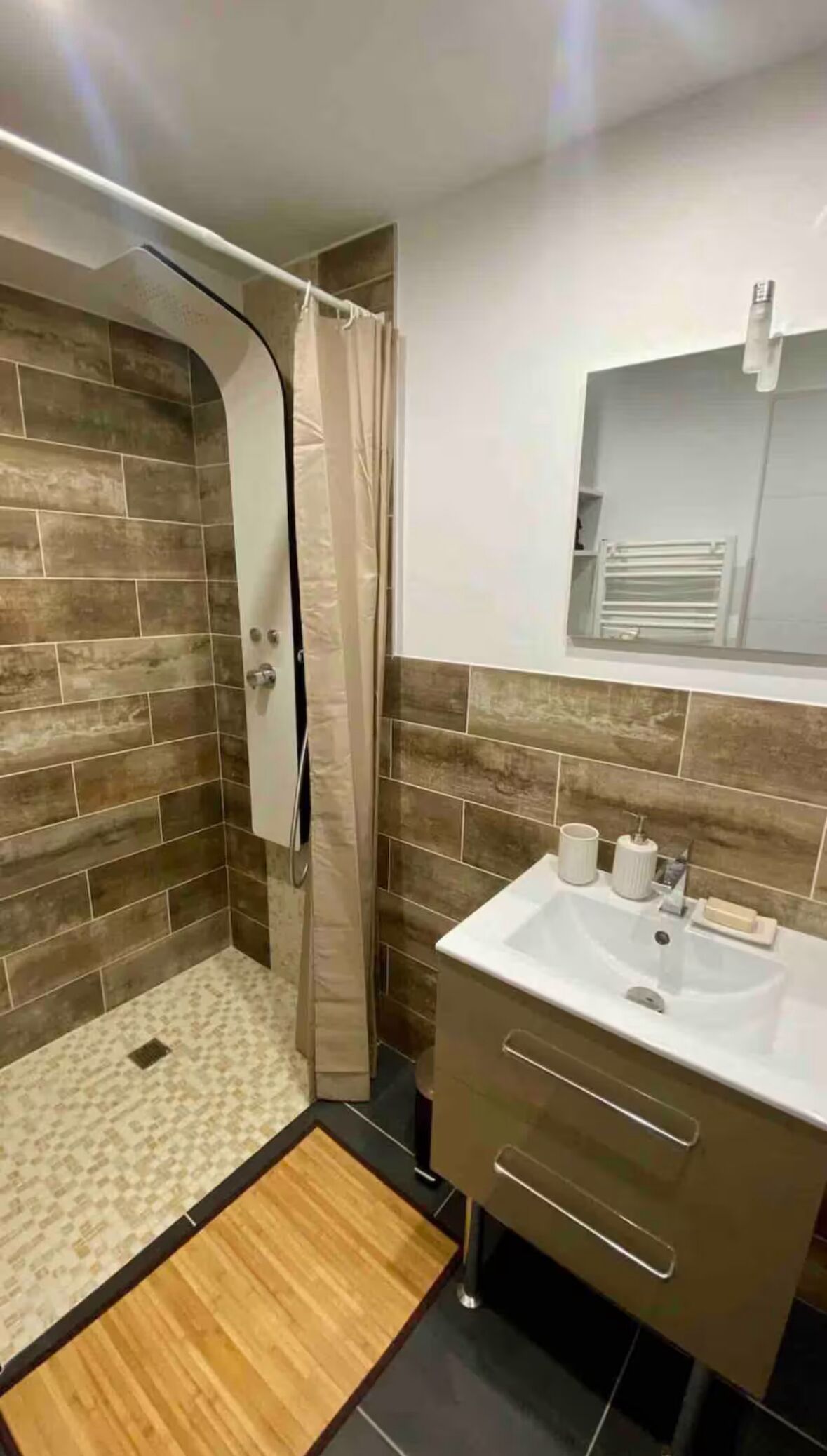 A bathroom with a shower, a sink, and a mirror.