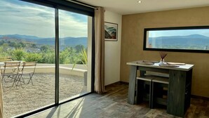 Ein Zimmer mit einer großen Schiebeglasdoor, die zu einem Außenbereich mit Tisch und Stühlen führt.