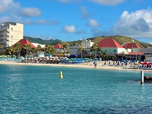 A beachside hotel with a pool, sun loungers, and umbrellas.