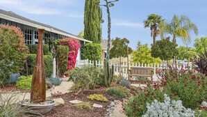 A garden with a variety of plants, a tall cactus, and a bench. - Garden Sanctuary • Fire Pit • Kitchen & Privacy (San Jose)