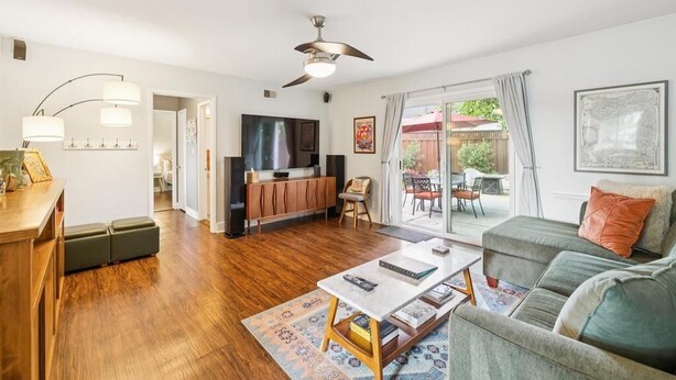 A modern living room with a flat-screen TV, a ceiling fan, and a dining area with outdoor seating. - Garden Sanctuary • Fire Pit • Kitchen & Privacy (San Jose)
