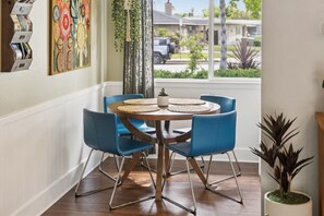 A dining area with a round wooden table, blue chairs, and woven placemats.
