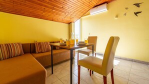 A cozy room with a wooden ceiling, a sofa with striped cushions, a dining table with chairs, and a window. - Stunning apartment in Povljana with WiFi (Povljana)