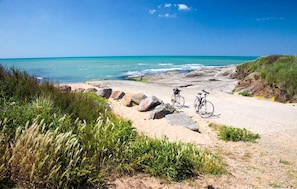 Un sentier côtier avec deux vélos garés sur le côté, qui mène à la plage.