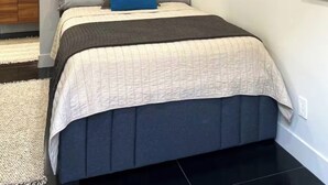 A modern bedroom with a large bed, a wall-mounted painting, a framed quote, and a window with blinds. - Serenity by the Lake. Beautiful neighborhood I short walk to lake and trails (Chula Vista)